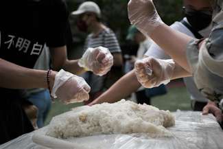 Community members punching sticky rice to turn it into ciba