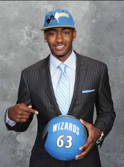 an image of John Wall in dress suit and team hat holding a basketball