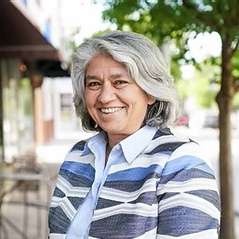 Sen. Lisa Grafstein smiling and wearing a striped blue and gray shirt. 