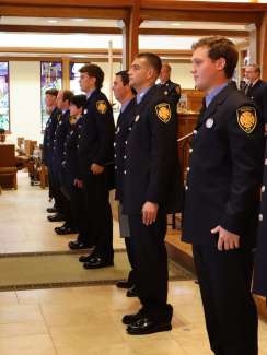 Several graduates stand in formation dressed in fire uniform