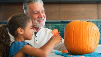 a grandparent and child with a pumpkin