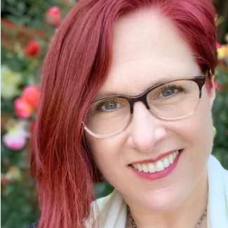 Smiling artsy white woman with bright red glasses. 