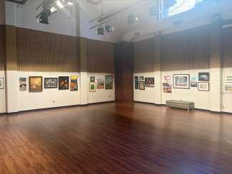 paintings hanging in a large room with white walls and a wooden floor