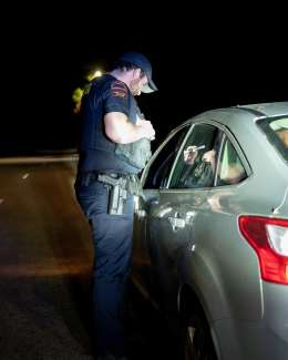 Raleigh police officer shining flashlight into driver window during a traffic stop