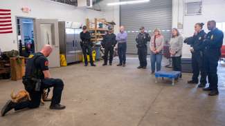 Ms. Parker and a friend look on with other officers as an officer handles his K9.