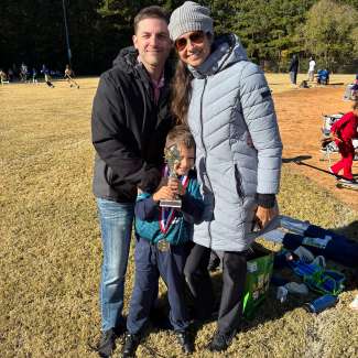 flag football player holding trophy with parents