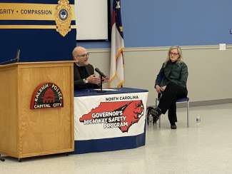 Mayor Cowell sits to the right of Mark Ezzell who is at the microphone during the press conference