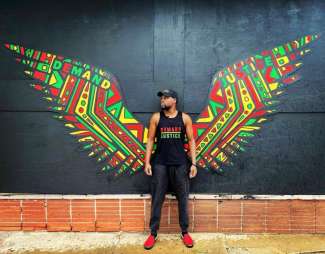 Image of a man standing in front of a large colorful pair of wings