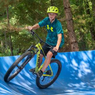 child on pump track wearing safety gear