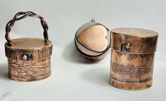 Three copper containers, one with a floral pattern, one with a heart and one with music notations