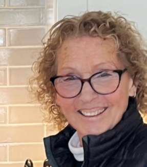 Photo of woman in glasses with short curly hair smiling