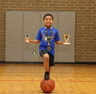 a boy holding two trophies and a medal around his neck