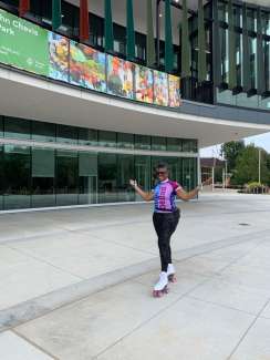 a person in front of a building smiling and wearing skates