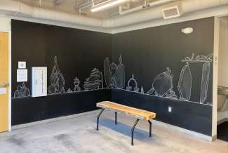 Picture of a black chalk wall with a drawing of piled rocks on it.
